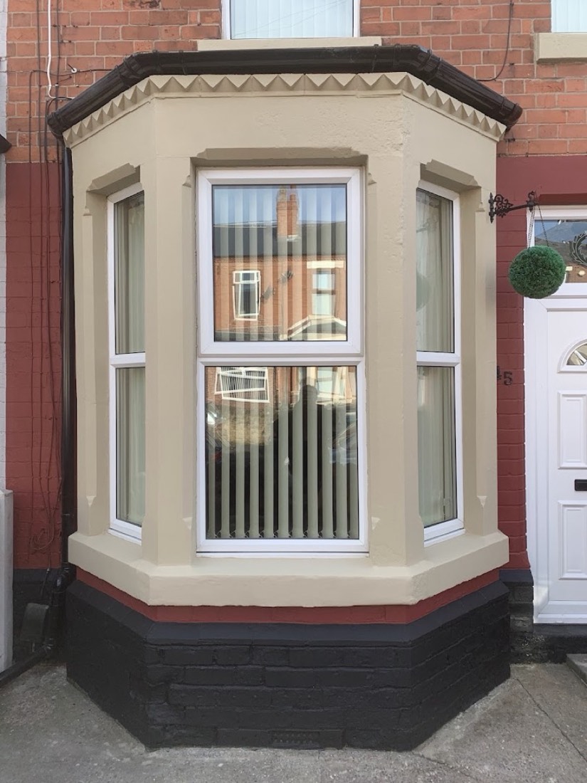Restored and painted rendered bay window with new roof trim